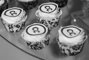 Black and white photograph of cupcakes with the CC logo on .