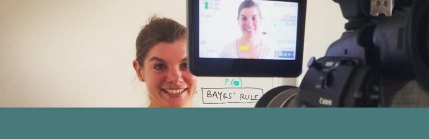 Woman standing in front of a whiteboard being recorded on a professional video camera