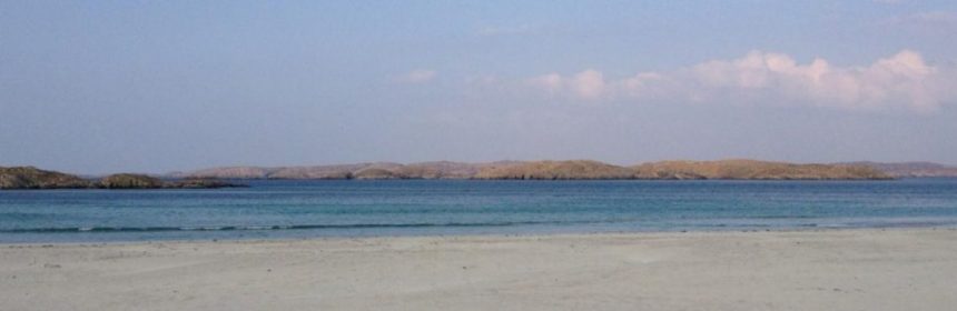 Shoreline with beach, sea, and mountains in the distance