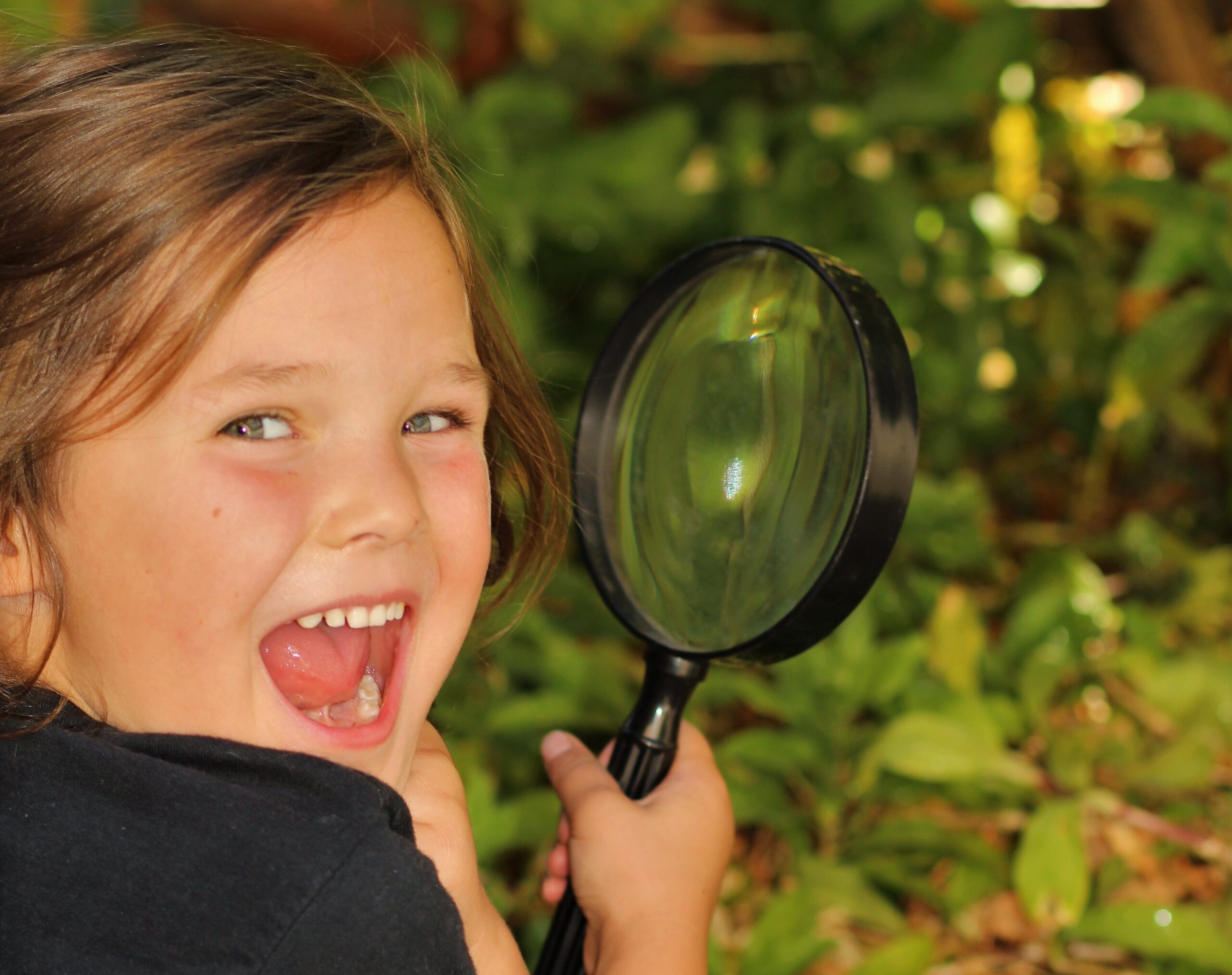 Photograph of a child with a magnifying glass