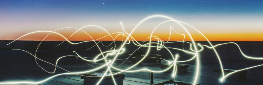 Digital image of light trails against a sunset background