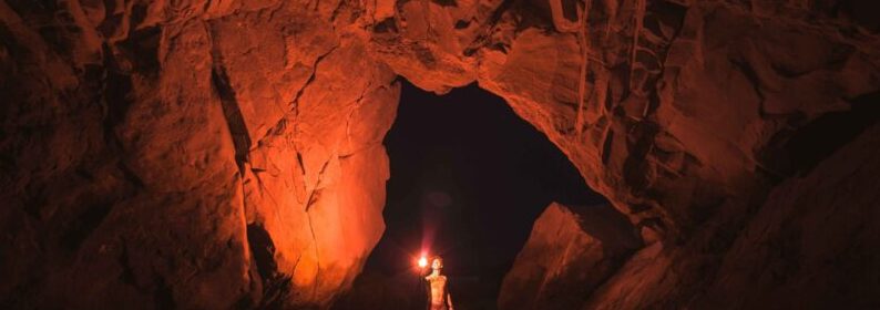 Person holding lamp inside cave