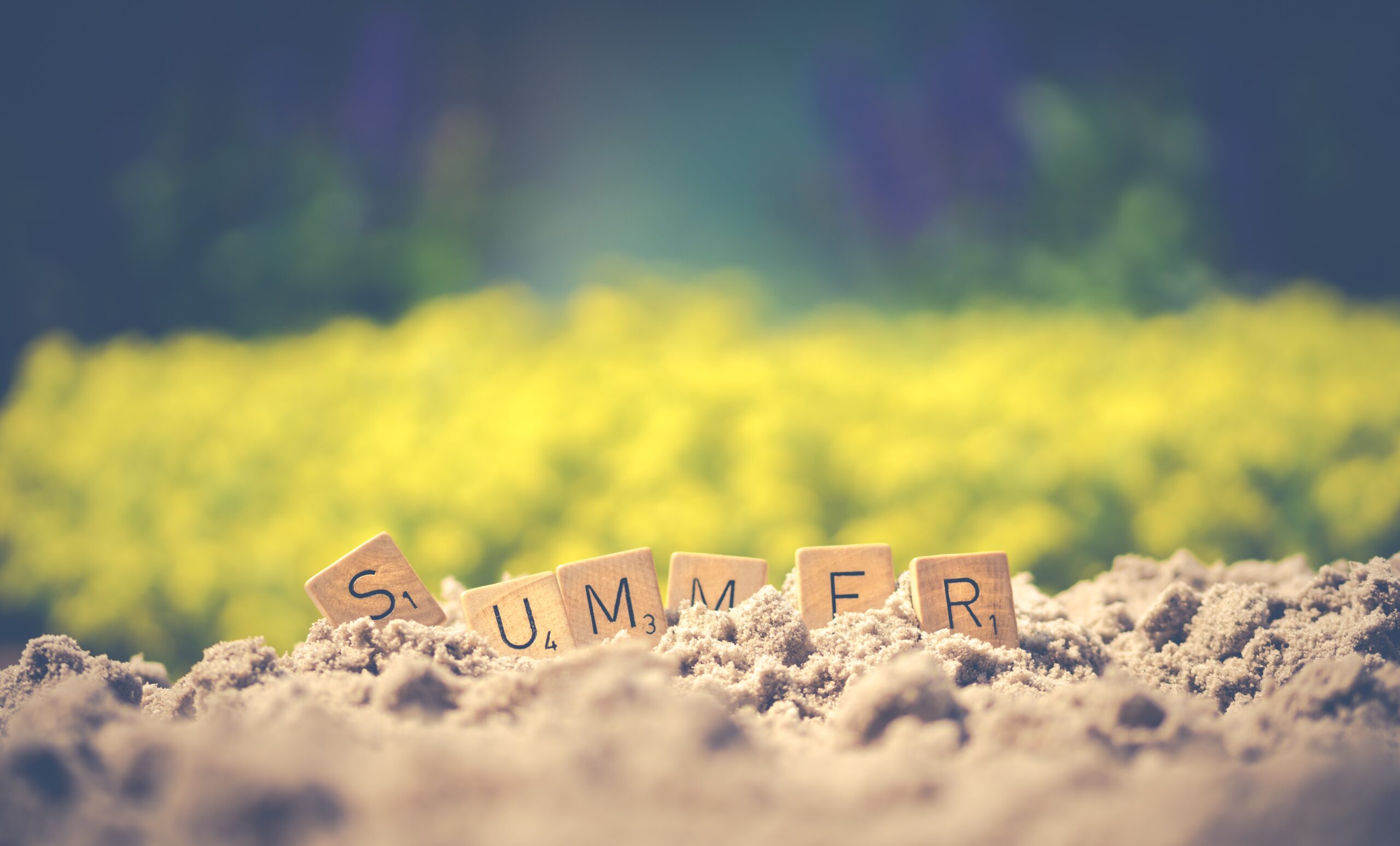 scrabble tiles spelling out Summer in the sand